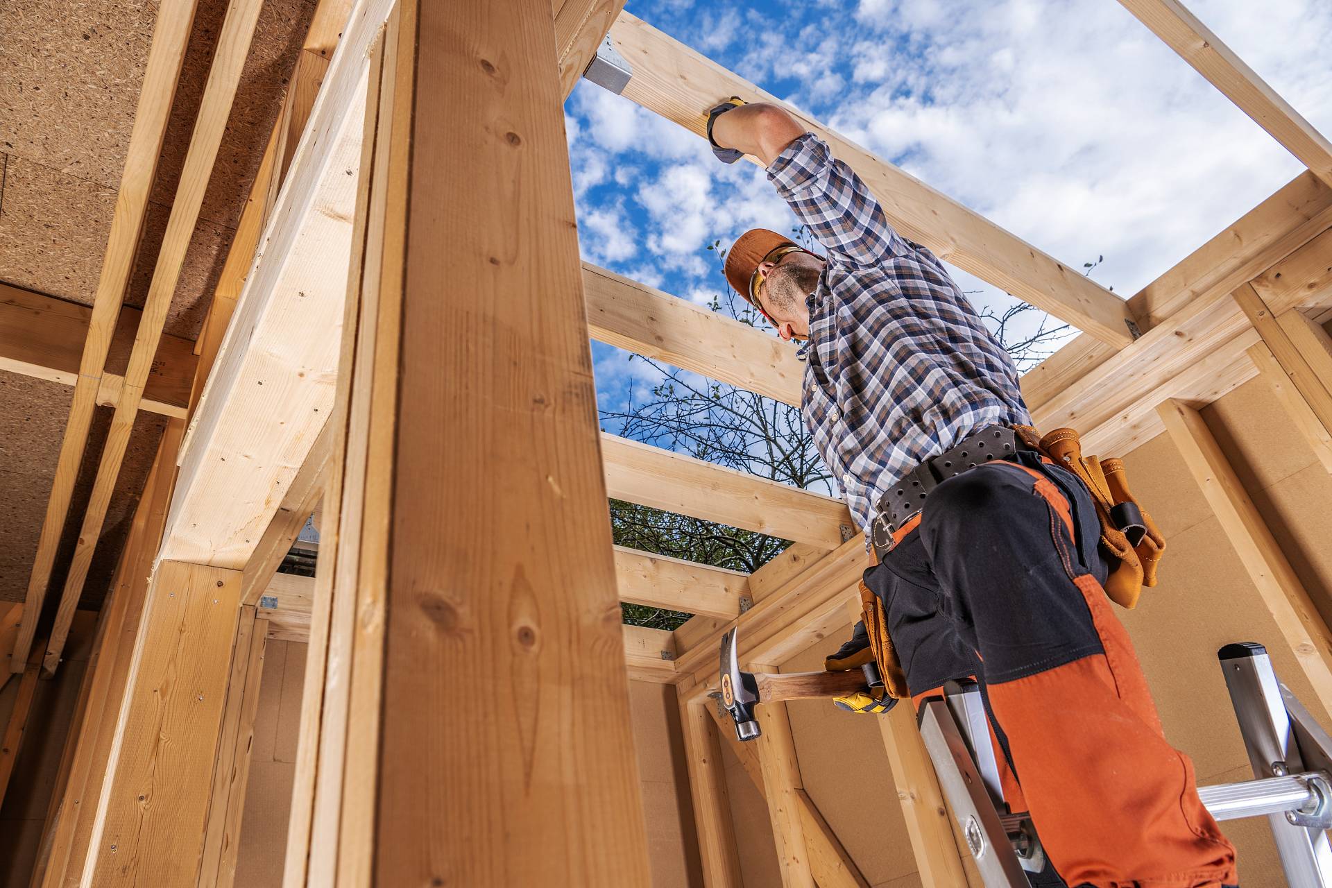 Zimmerer bei der Montage von Dachbalken in Holzrahmenbauweise – Handwerksarbeiten beim Hausbau.