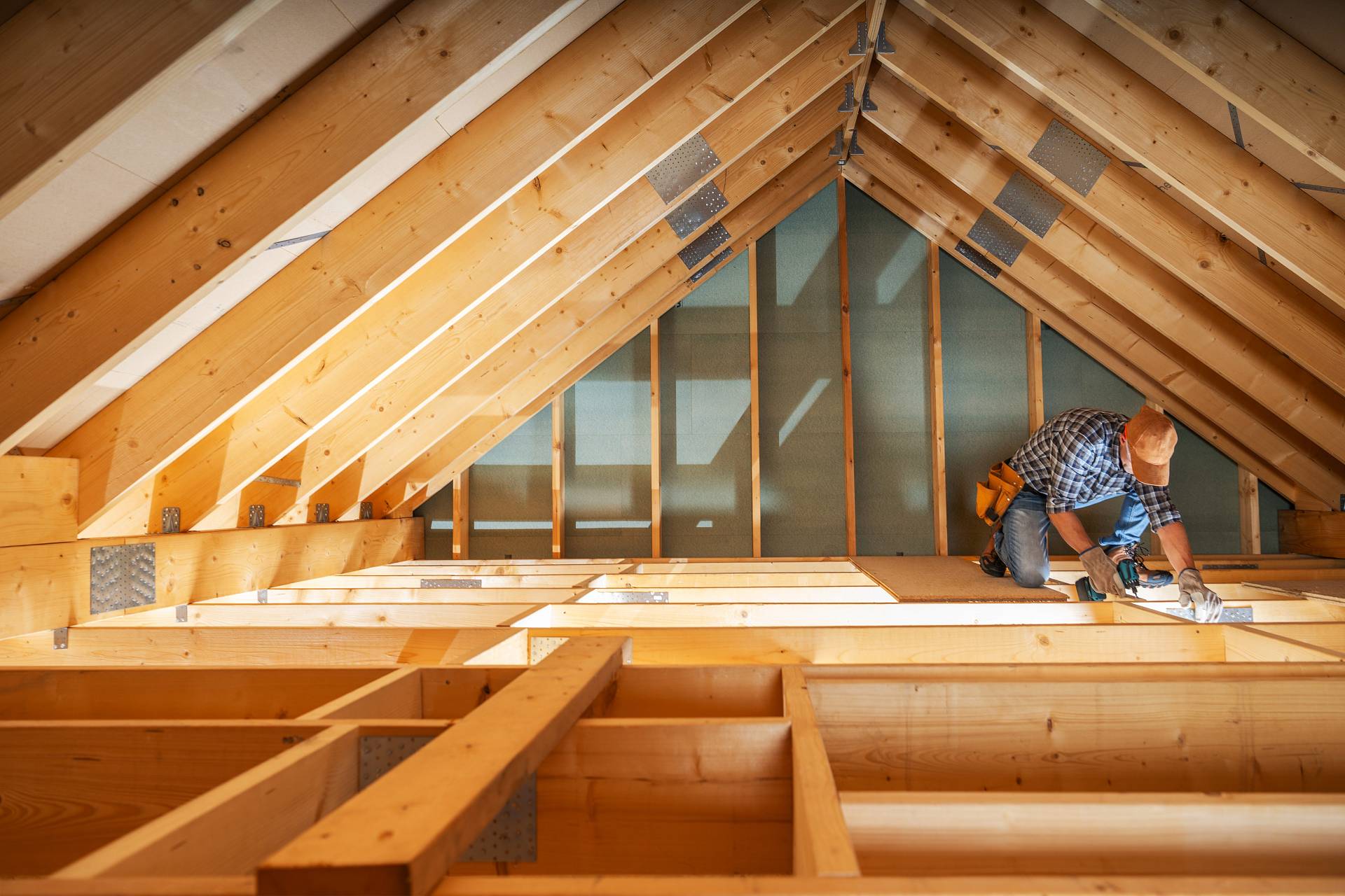 Zimmermann bei Arbeiten im ausgebauten Dachgeschoss mit sichtbarem Sparrenaufbau und Holzständerkonstruktion.