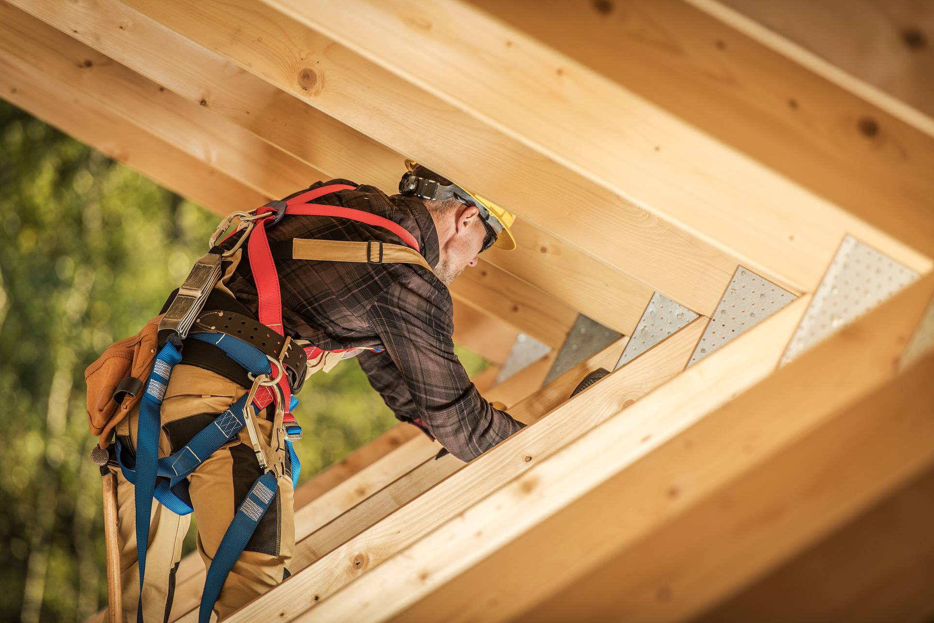 Zimmerer mit Absturzsicherung bei der Montage einer Dachkonstruktion aus Holz – Arbeiten am Dachstuhl.