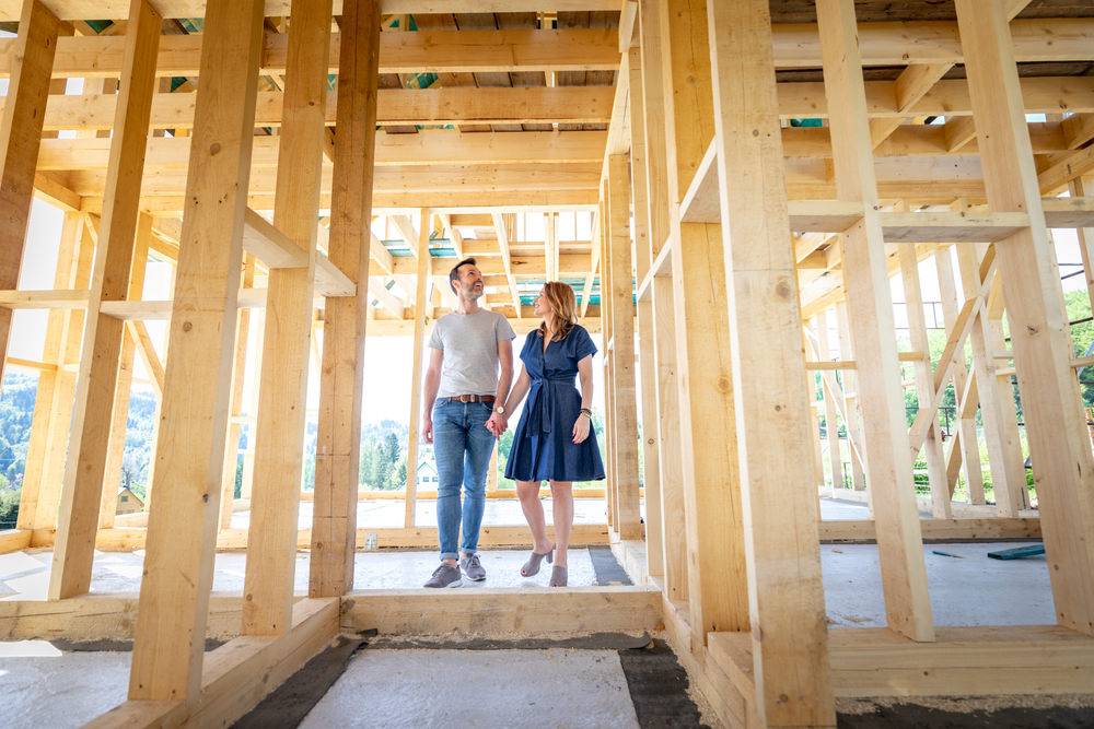 Junges Paar besichtigt den Rohbau ihres zukünftigen Eigenheims in Holzrahmenbauweise – Zimmerei realisiert modernen Holzhausbau.
