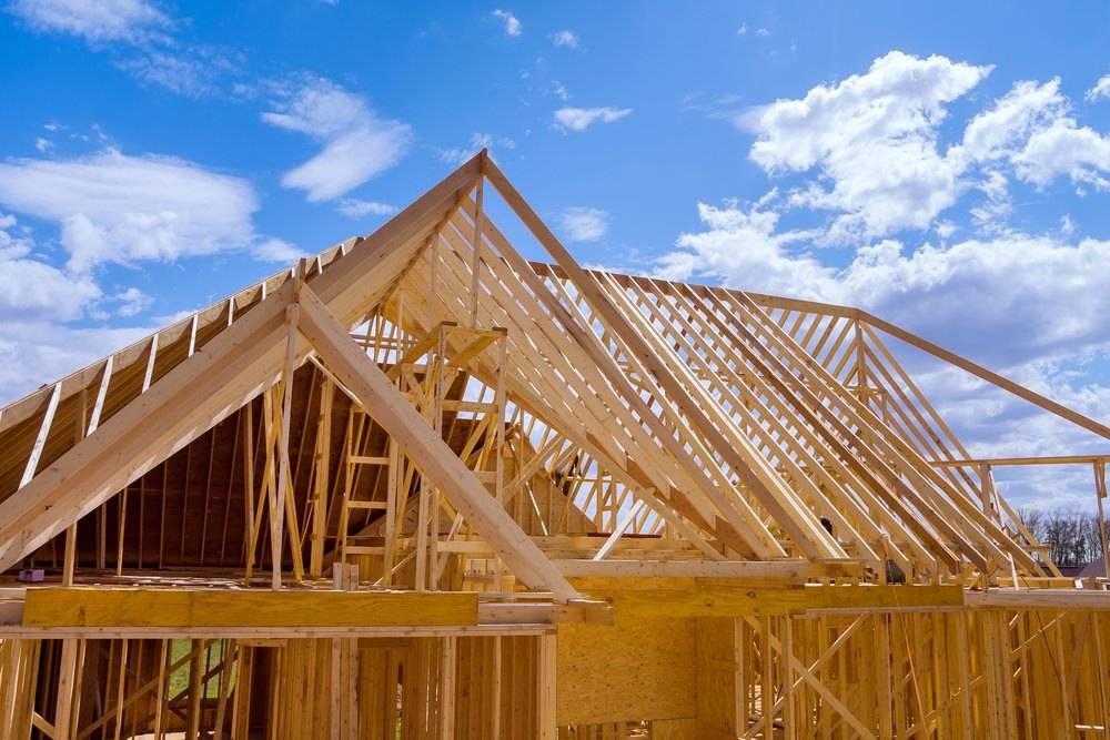 Bau eines traditionellen Dachstuhls in Holzrahmenbauweise unter freiem Himmel – präzise Zimmererarbeit beim Neubau eines Holzhauses.