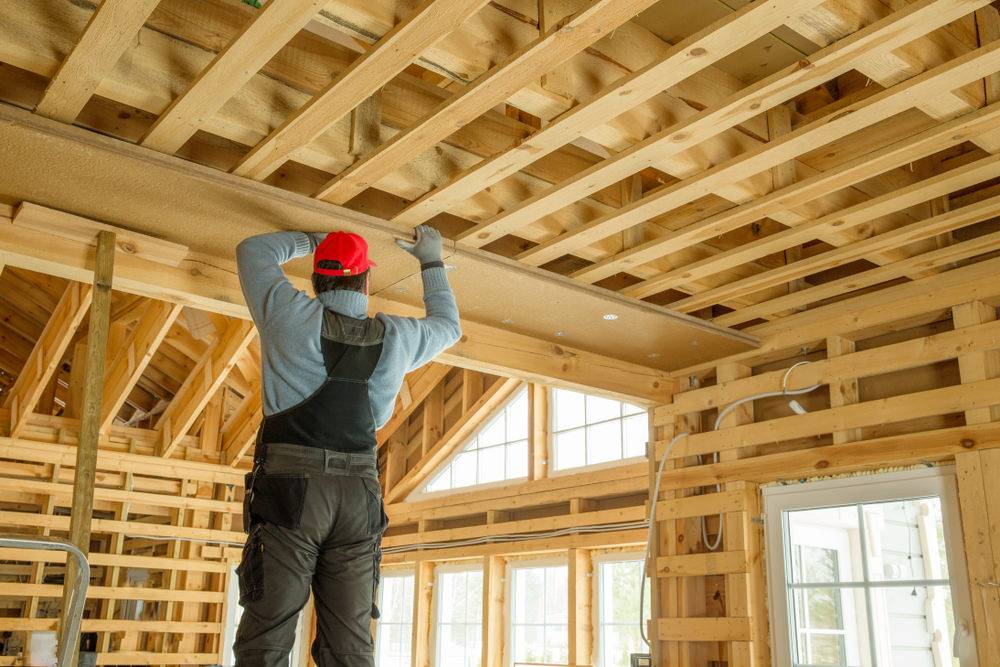 Zimmerer montiert Deckenplatte im Innenausbau eines Holzhauses – professioneller Ausbau mit natürlichem Baustoff.