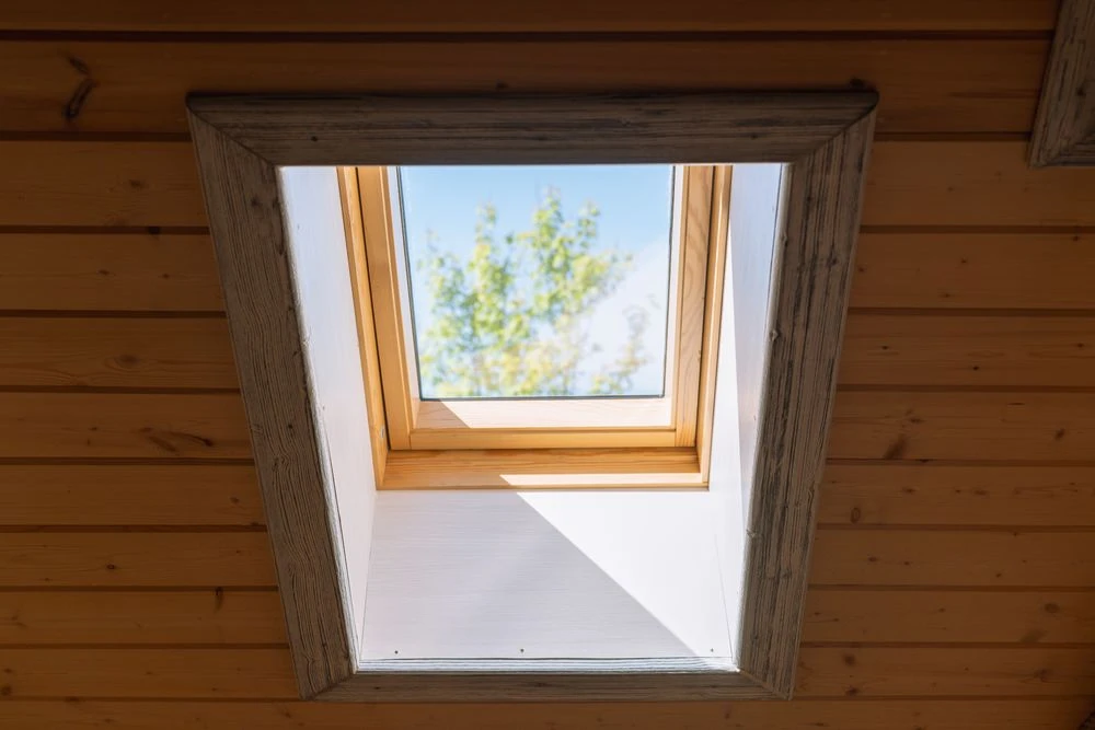 Modernes Dachfenster mit Holzrahmen und Innenverkleidung – natürlicher Lichteinfall im ausgebauten Dachgeschoss.