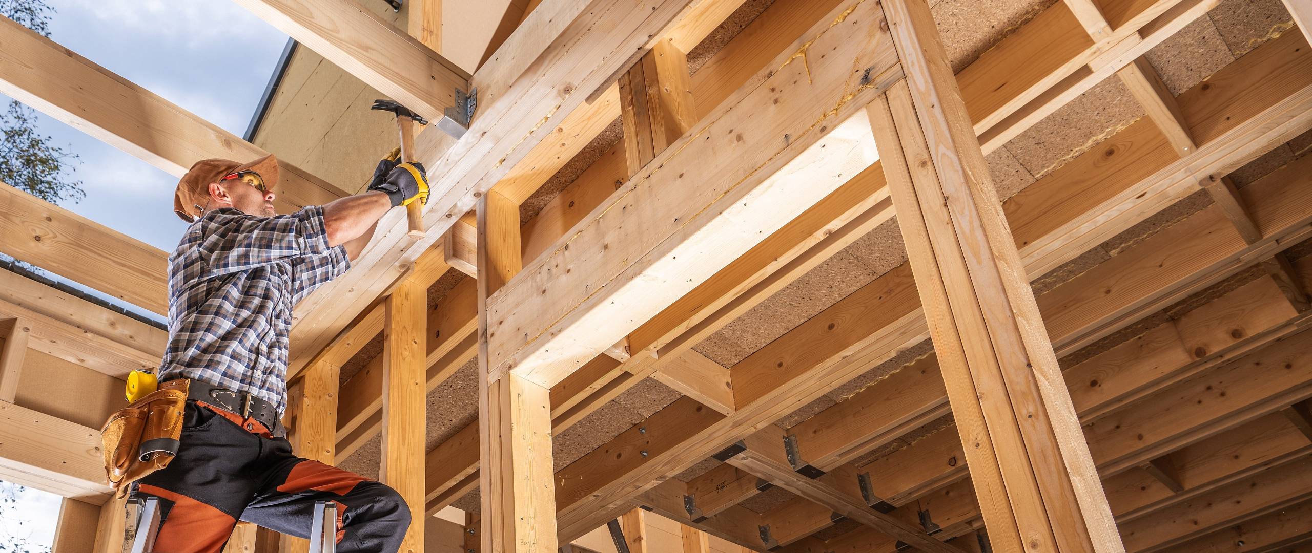 Zimmermann bei Holzbauarbeiten an Dachkonstruktion – nachhaltiger Hausbau mit Holzrahmen in moderner Bauweis